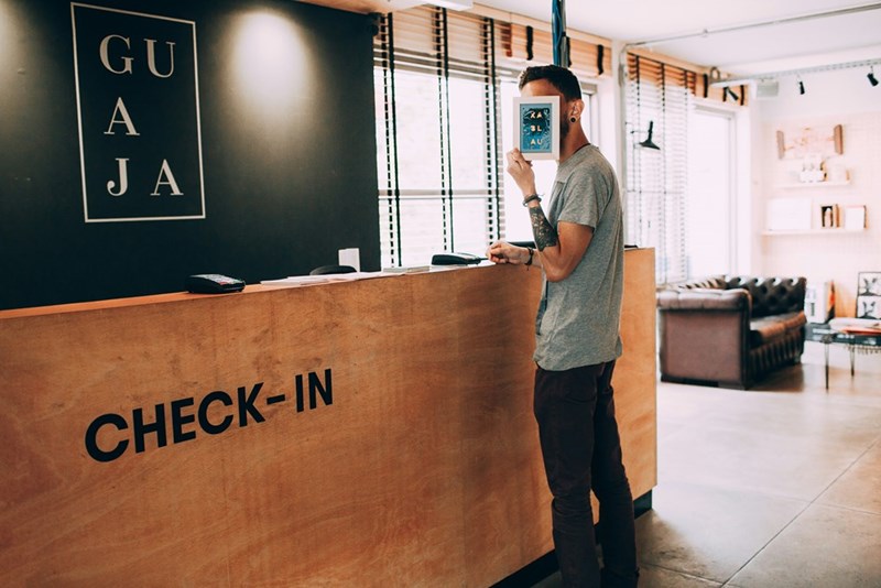 A man standing at the front desk of a hotel, representation.
