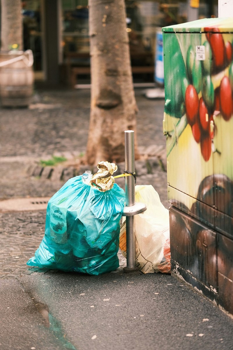 a trash can sitting on the side of a road
