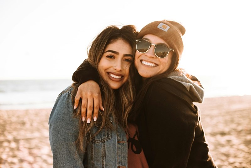 two women hugging each other at a beach