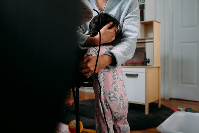 Parent comforting a young child inside the family home.
