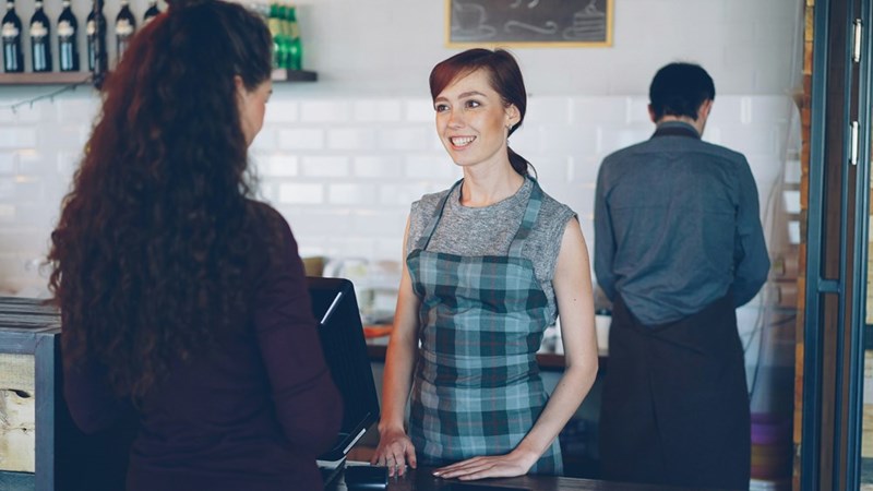 a barista smiles while talking to a customer
