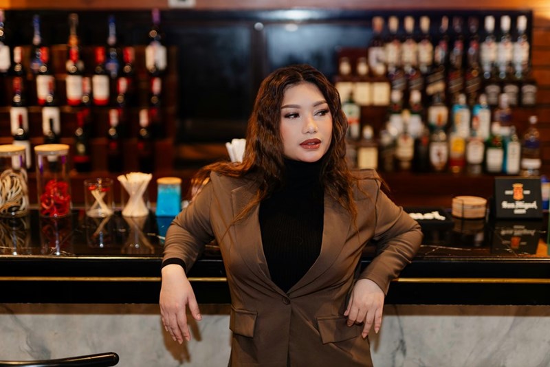 woman in suit leaning on a bar counter