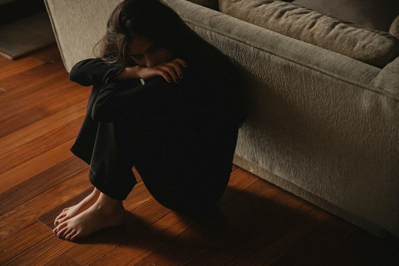 Upset woman sitting on the floor infront of a couch.