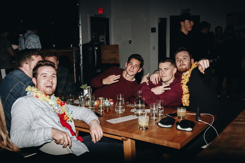 a group of men sitting around a wooden table having fun