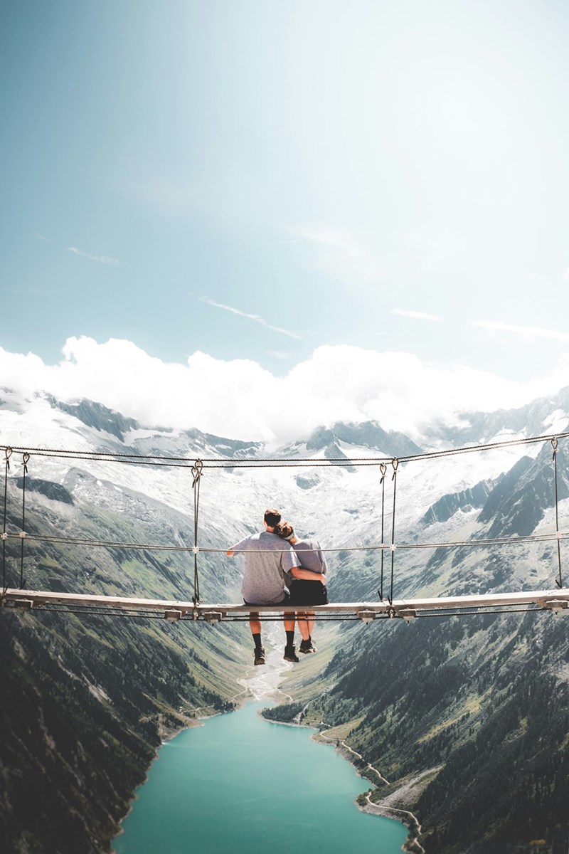 man and woman sitting on hanging bridge