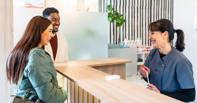 Image representing a couple smiling at the receptionist