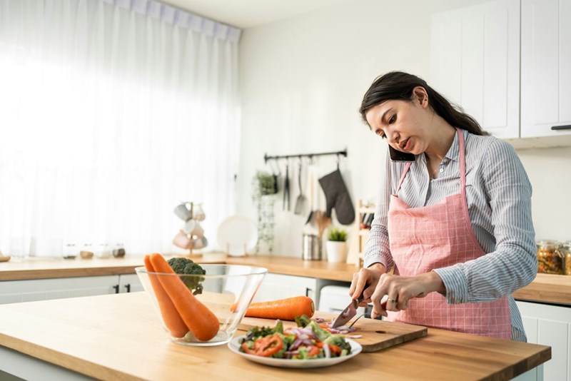 Home cook preparing fresh vegetables while multitasking with a phone call.