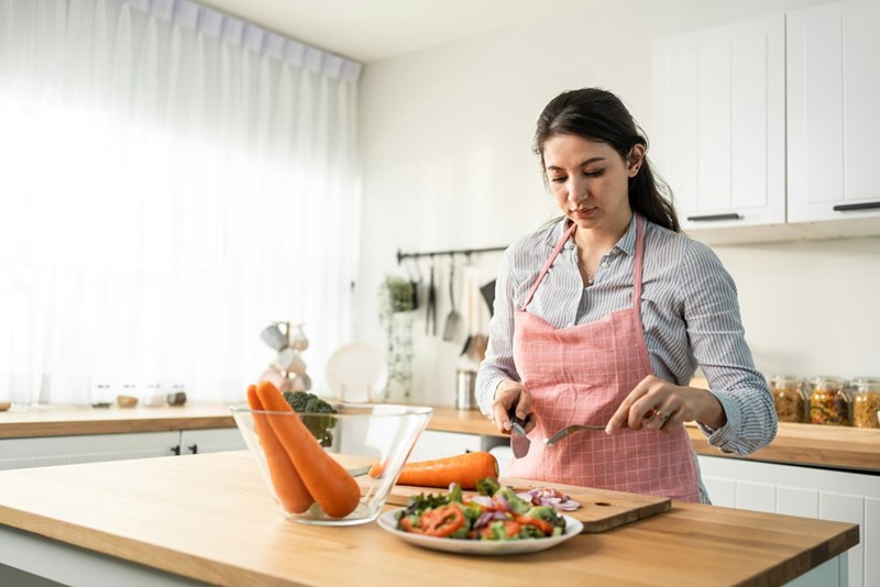 Woman making a healthy salad with fresh ingredients.