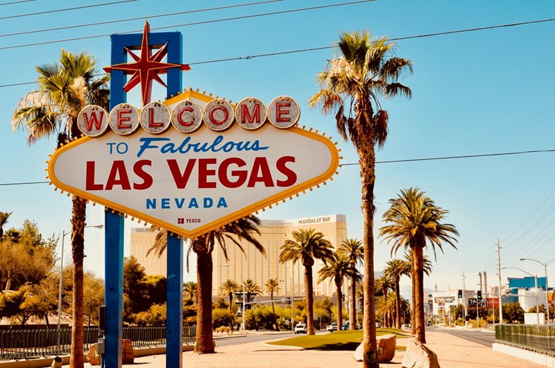 The iconic Welcome to Fabulous Las Vegas sign surrounded by palm trees on a sunny Nevada day.
