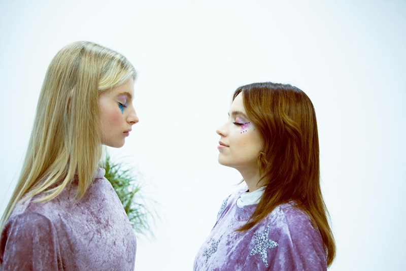 two women in profile facing each other with their eyes closed
