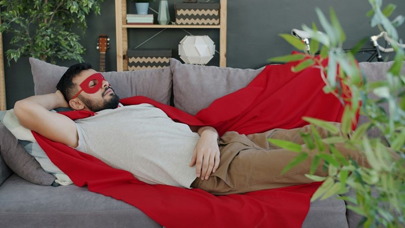 man in superhero costume sleeping on sofa