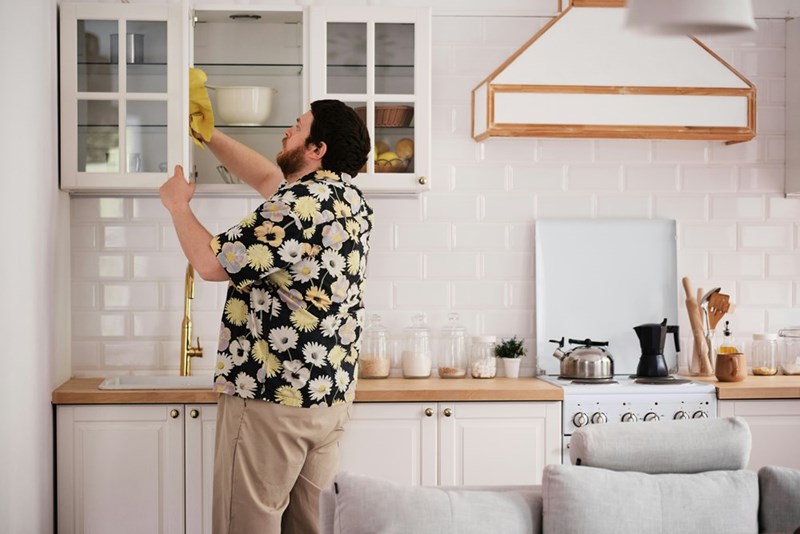 Man wearing floral shirt tidying the kitchen.