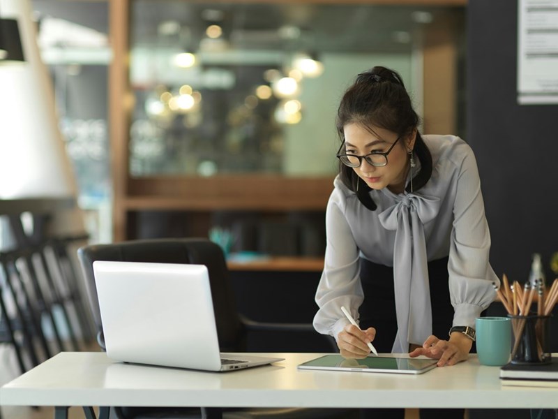 Professional employee reviewing digital documents and project plans in a modern office environment.