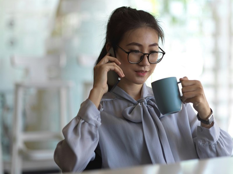 Office professional enjoying a coffee break while taking an important phone call.