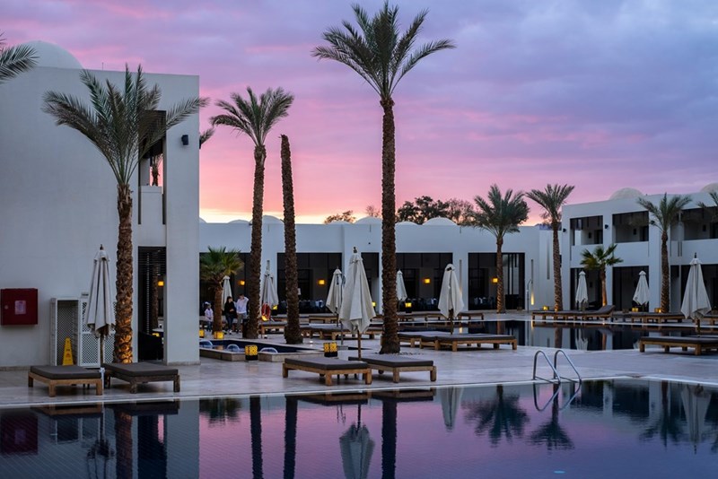 Representation of the outside of a hotel in a paradisiac place.