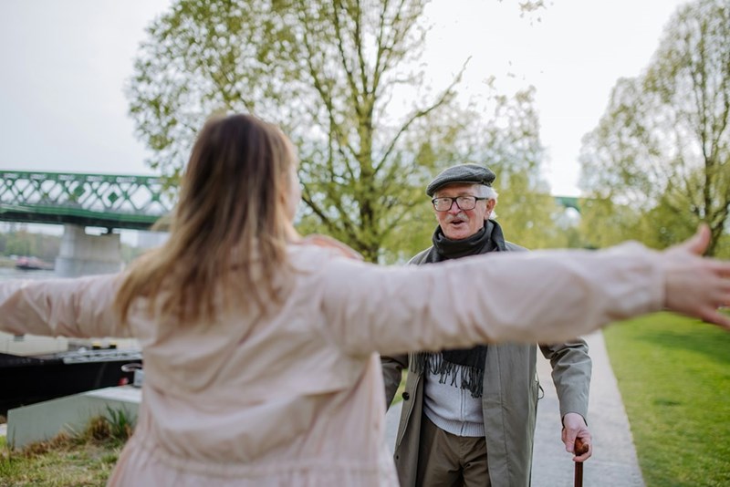 A representation of a father and adult daughter walking through a park during a Father’s Day outing.