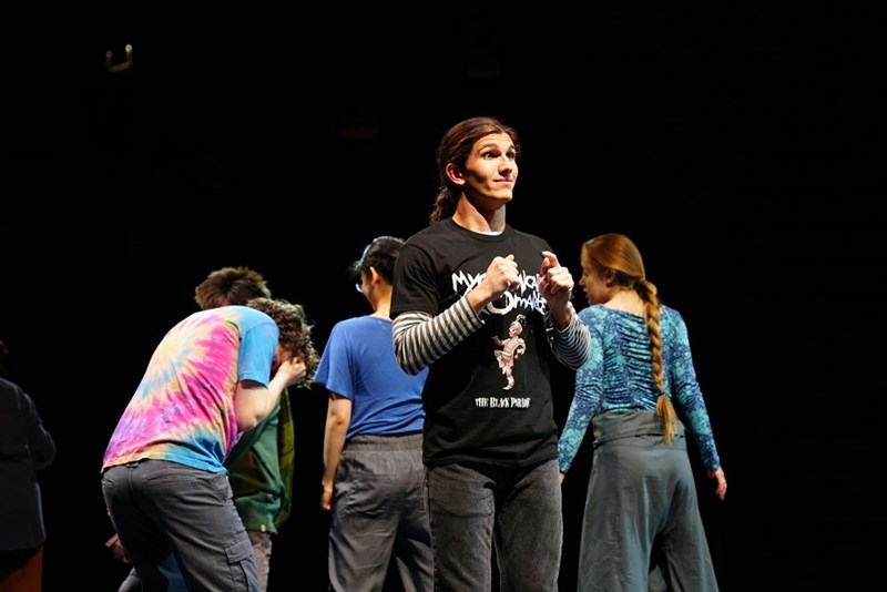 An illustrative image of an amateur theater stage representing the rehearsal group where two childhood friends reconnect years later.