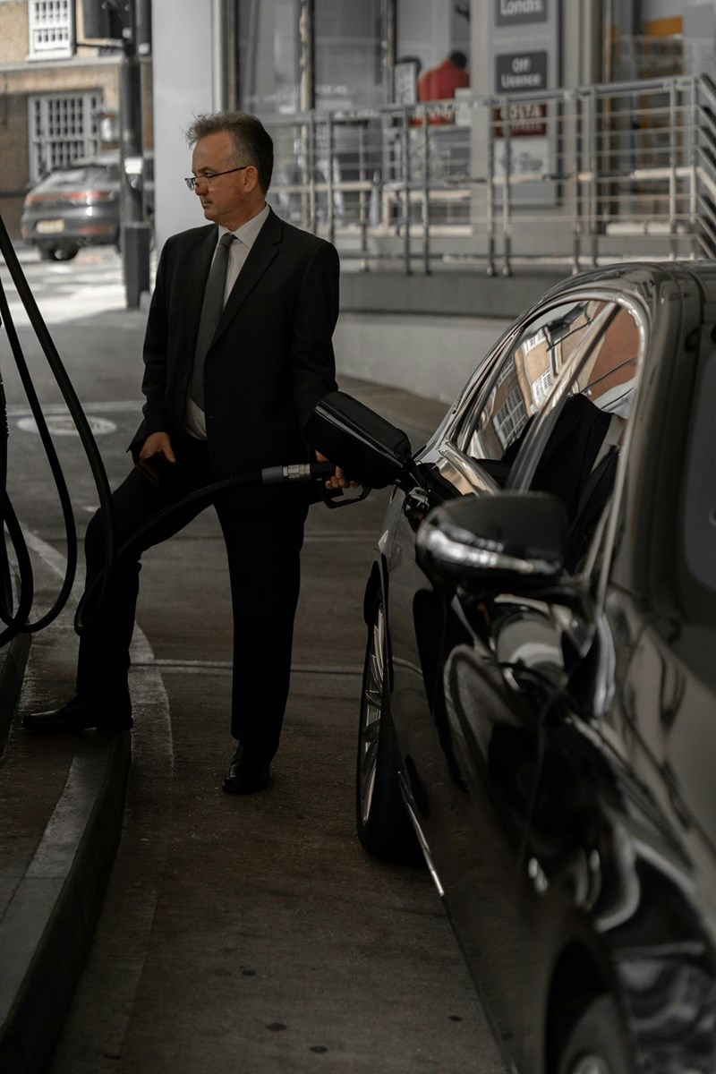 man in black suit pumping gas on a car