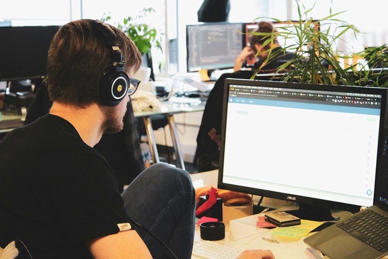 A man working at a computer with a headset.