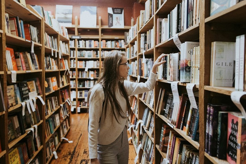 woman looking through books on shelves