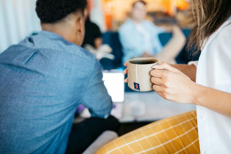 man in blue denim jacket sitting besides woman with mug