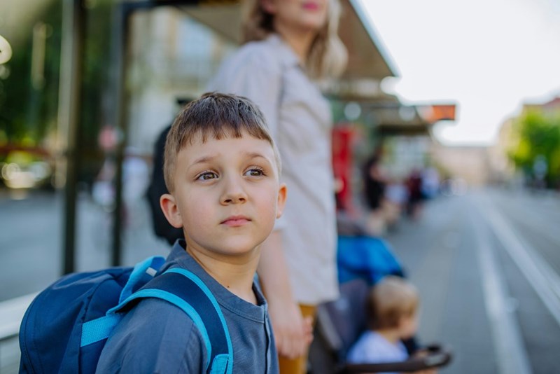A young boy waiting in a bus station, presented by models.