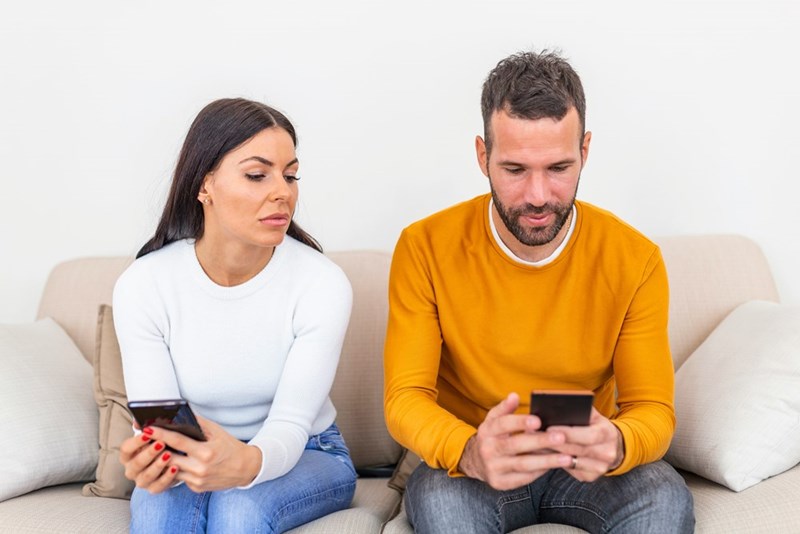 a couple on their phones on the couch