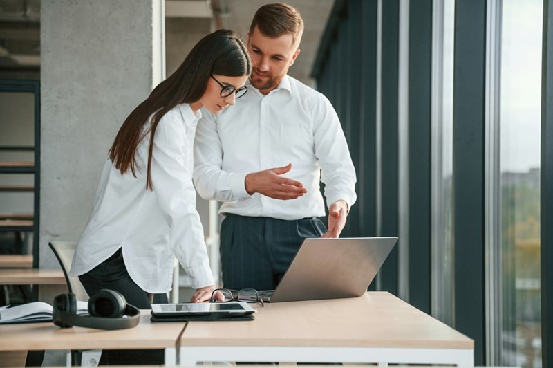 Woman and man working at a modern office looking at a computer.