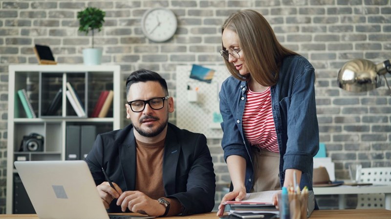 Woman and man looking at a laptop at an office.