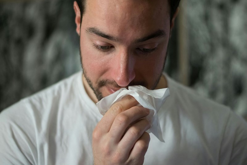 sick man blowing nose