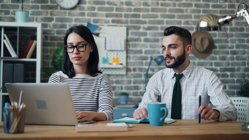 Coworkers work side by side at a shared desk