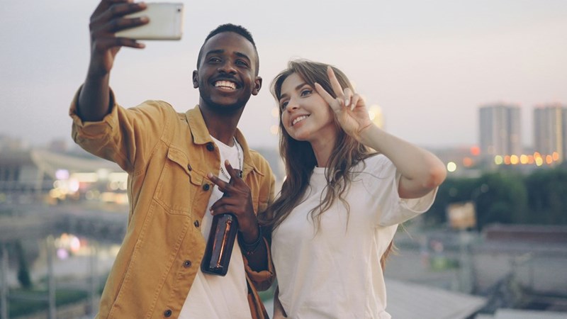 man and woman taking a selfie smiling and peace signs