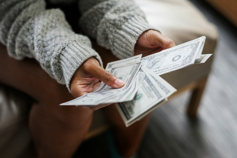 A model represents a wealthy stepmom holding cash, illustrating financial support used as leverage in a family conflict.