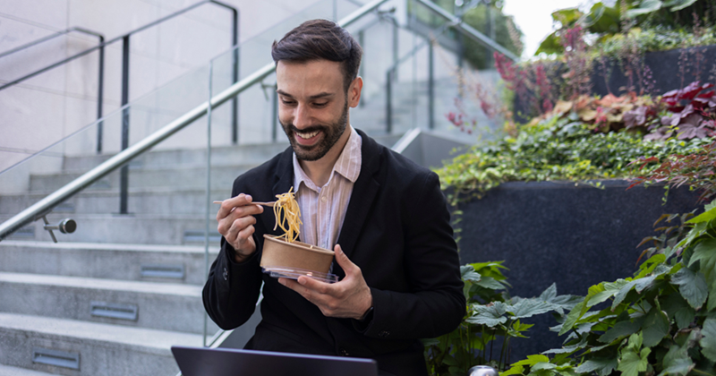 Businessman enjoying lunch break eating noodles outdoors