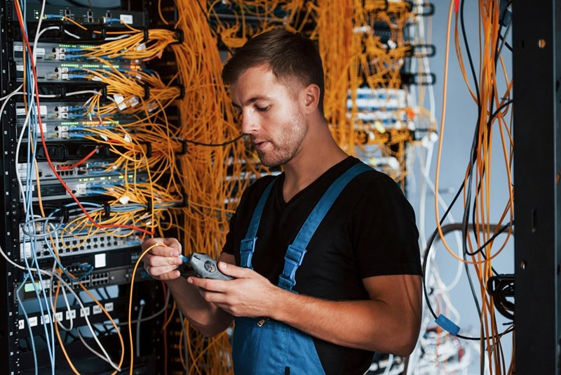 A technician works in a server room on a critical error with yellow cables around him