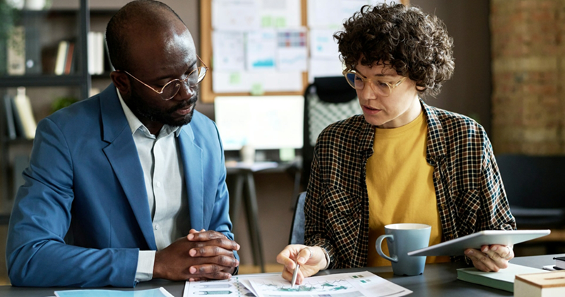 A manager and an employee examining business reports together