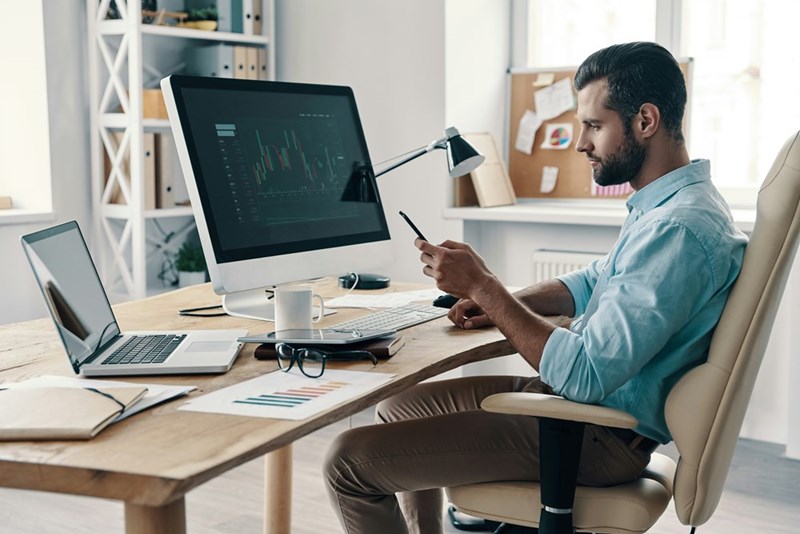A professional sits at a desk reviewing information on a computer