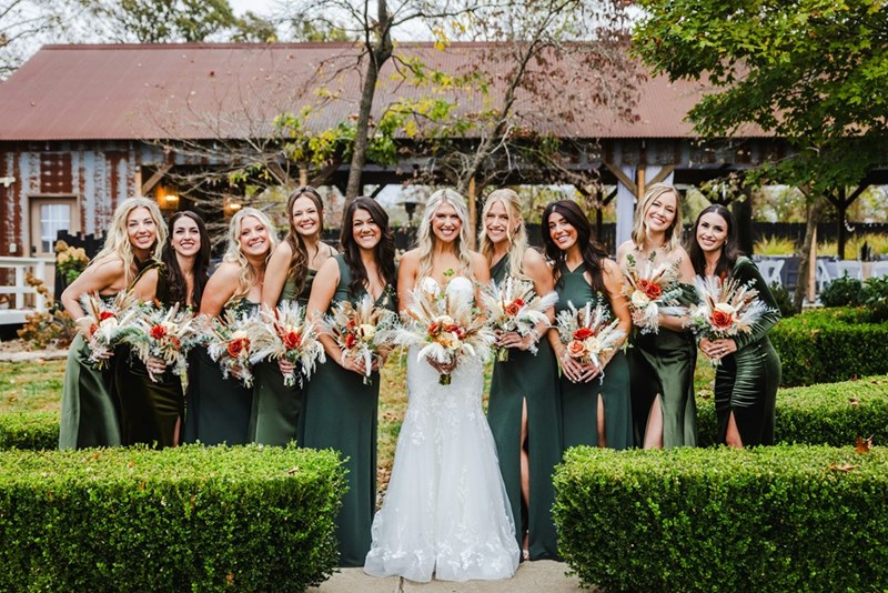 Bride poses with her bridesmaids holding bouquets during an outdoor wedding