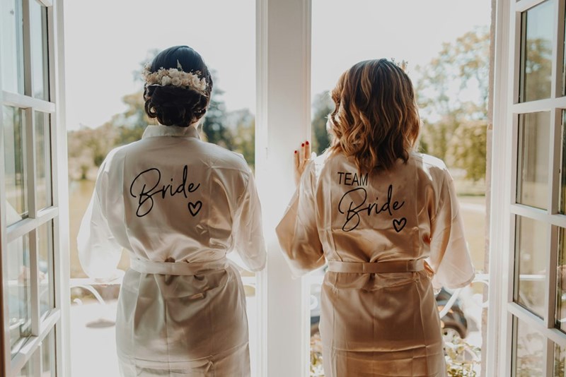 Bride and maid of honor wearing matching wedding robes before the ceremony,
