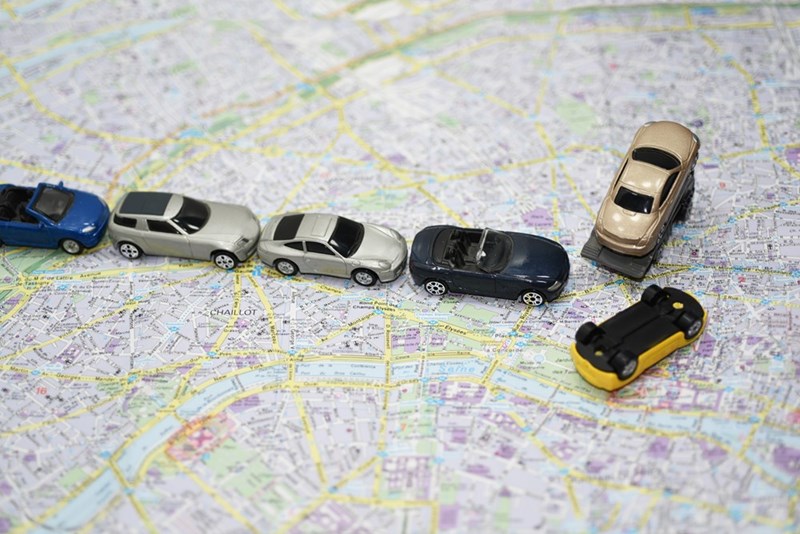 Toy cars arranged on a city map with one yellow car overturned near a line of vehicles.