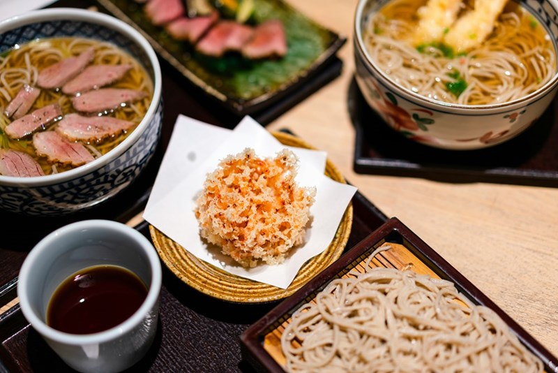 Different types of Japanese foods laying on top of a table, model image.