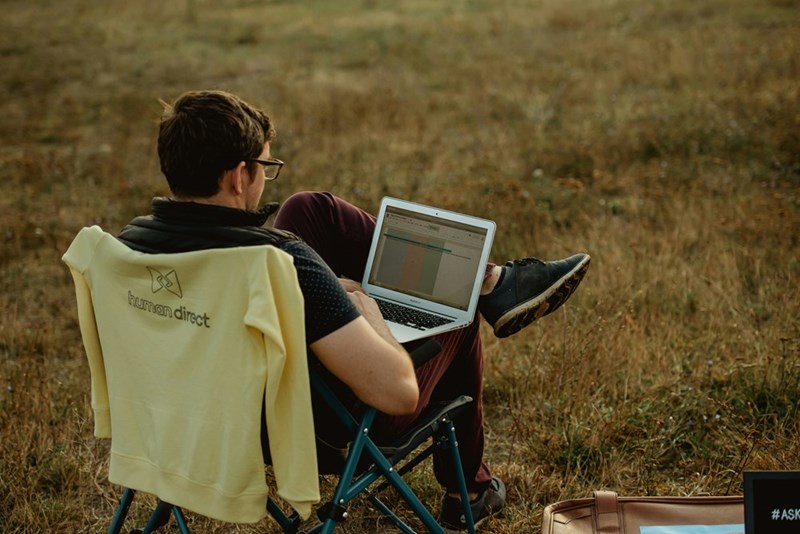 A man working on his computer in the middle of nowhere, model image.