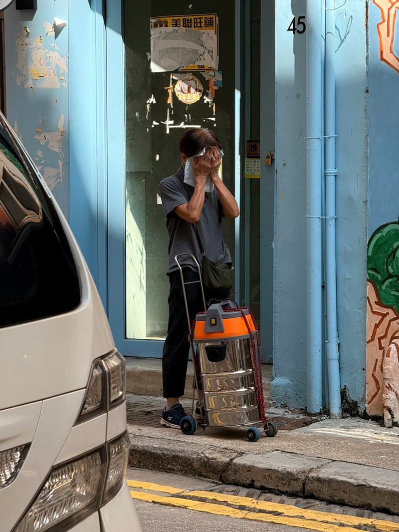 A man wiping sweat from his face in hot weather, capturing the discomfort of passengers stuck in a vehicle without air conditioning, represented by a model.