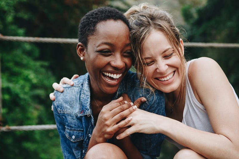 Two women hugging and smiling at the park.