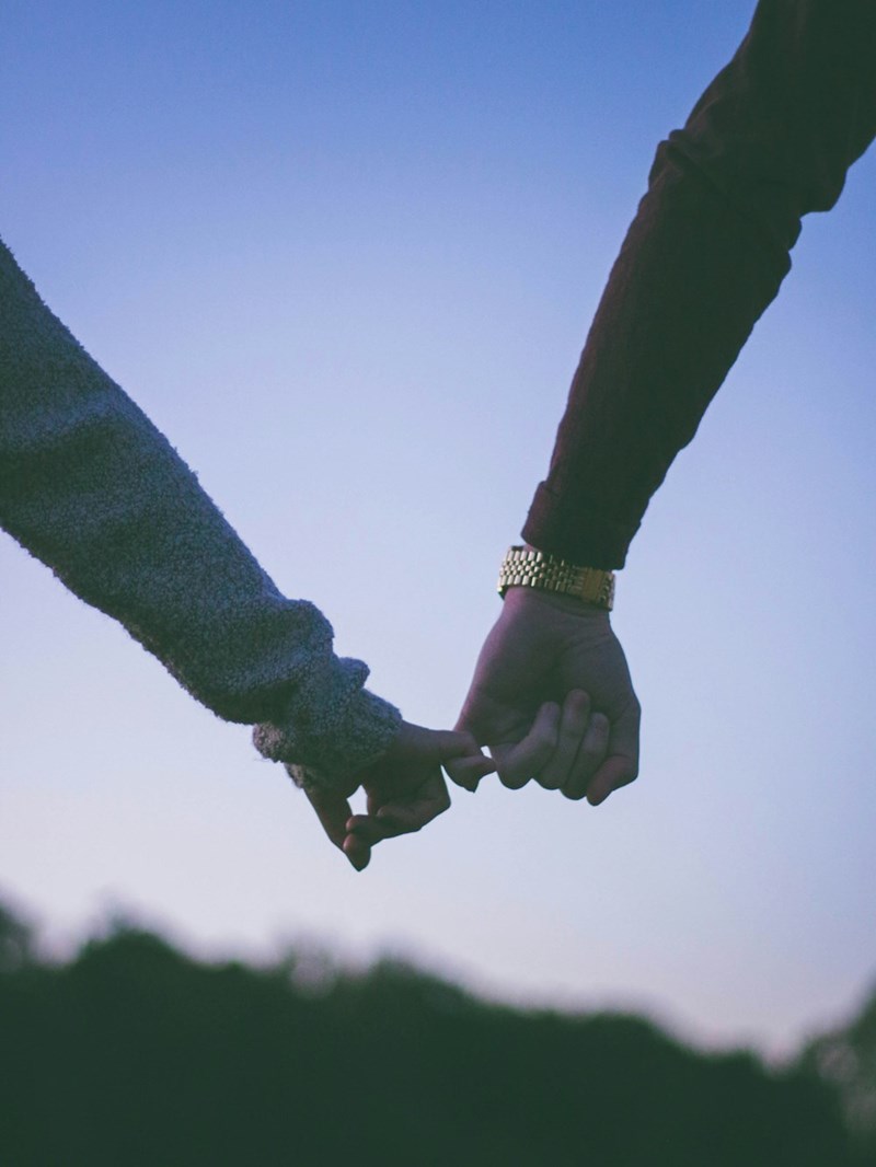 man and woman holding hands using pinky fingers