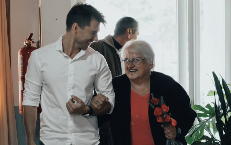 A young man and his grandmother walk through the doors of a hospital where she is staying