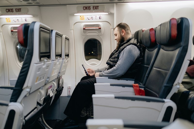 a tall man sitting in the emergency exit row so that he has enough room to stretch his long legs out.