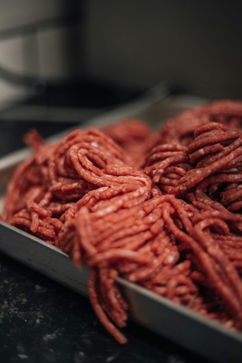 Ground beef, squeezed out of the package and into a pan.