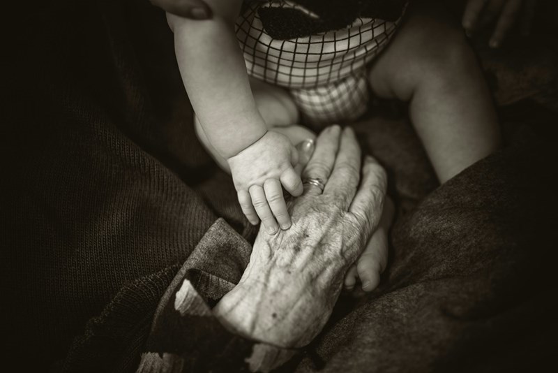 an old person holding a baby's hand