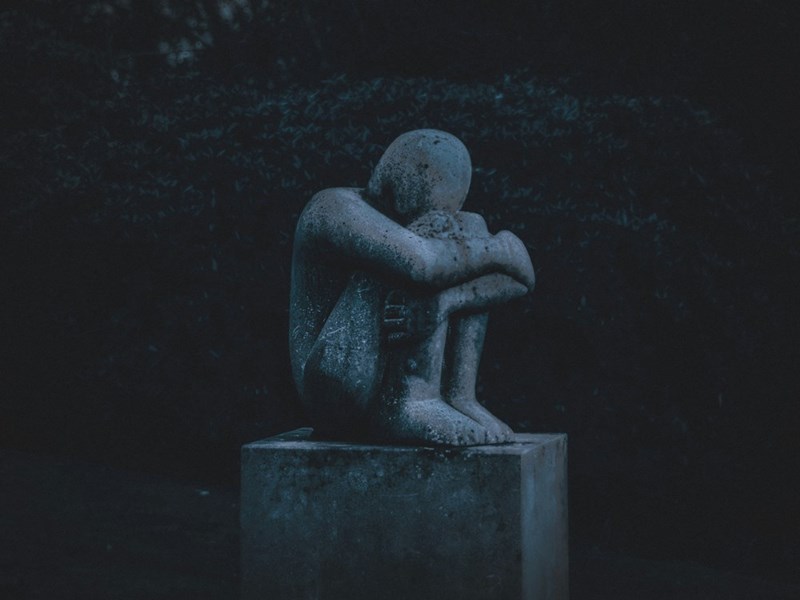 statue of a man hugging his knees